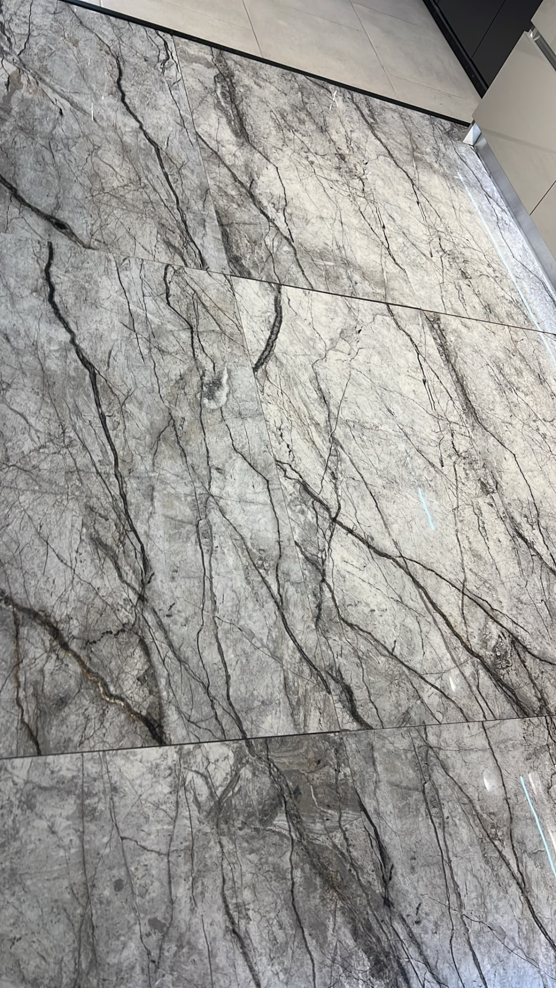 Carrelage gris veiné posé au sol, effet marbre